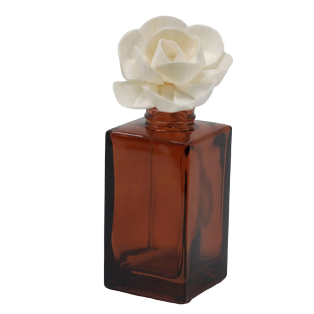Flor de madera sola en forma de loto sobre frasco de vidrio color ámbar cuadrado para difusor de aromas.