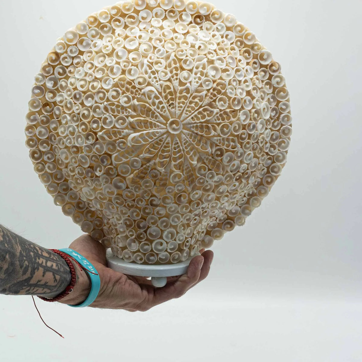 Lámpara boho redonda de 30 cm hecha a mano con pequeñas conchas marinas blancas dispuestas en un patrón floral detallado.