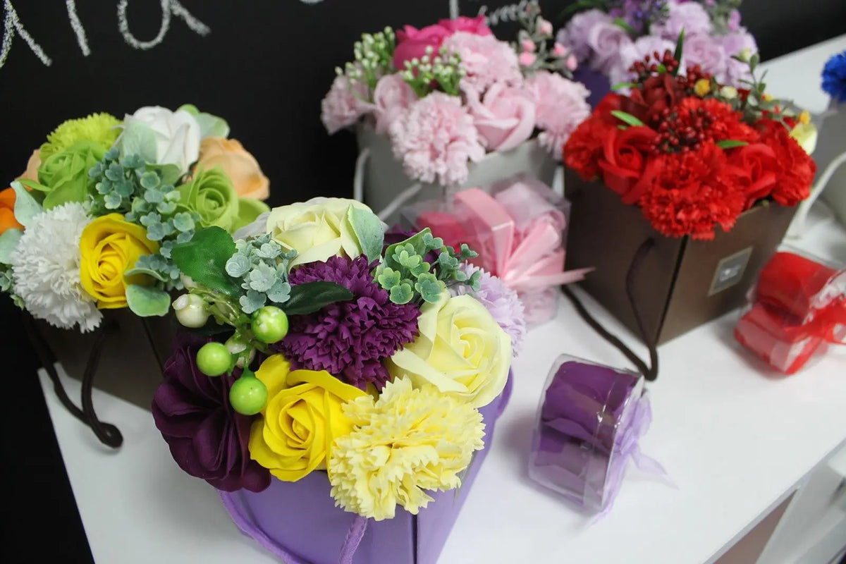 Bouquets de flores de jabón coloridas en cajas de regalo decorativas sobre una mesa blanca. Estilo romántico y floral.