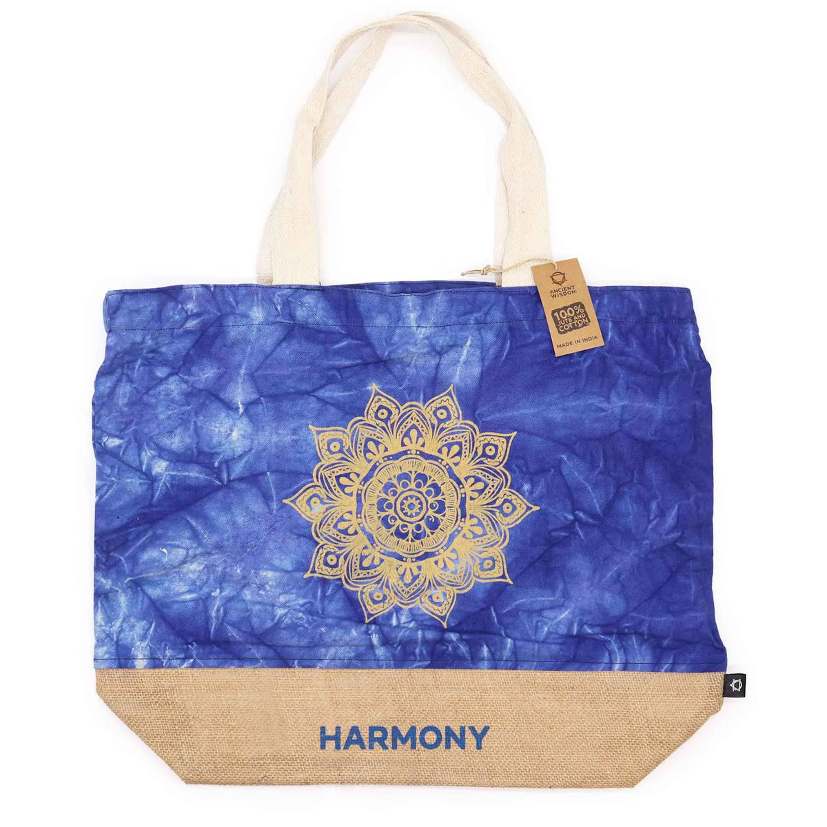 Bolsa de tela azul con estampado de mandala dorado, base de yute natural y asas de algodón, con el texto "HARMONY".