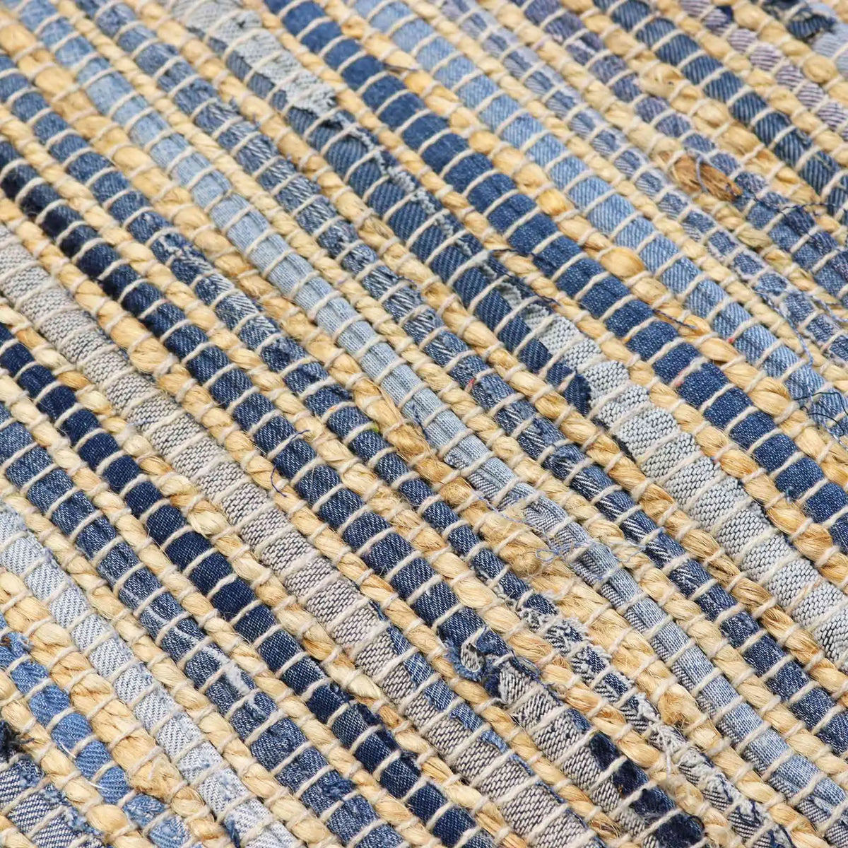 Primer plano de alfombra tejida artesanalmente con fibras de yute natural y tiras de algodón reciclado en tonos azules.