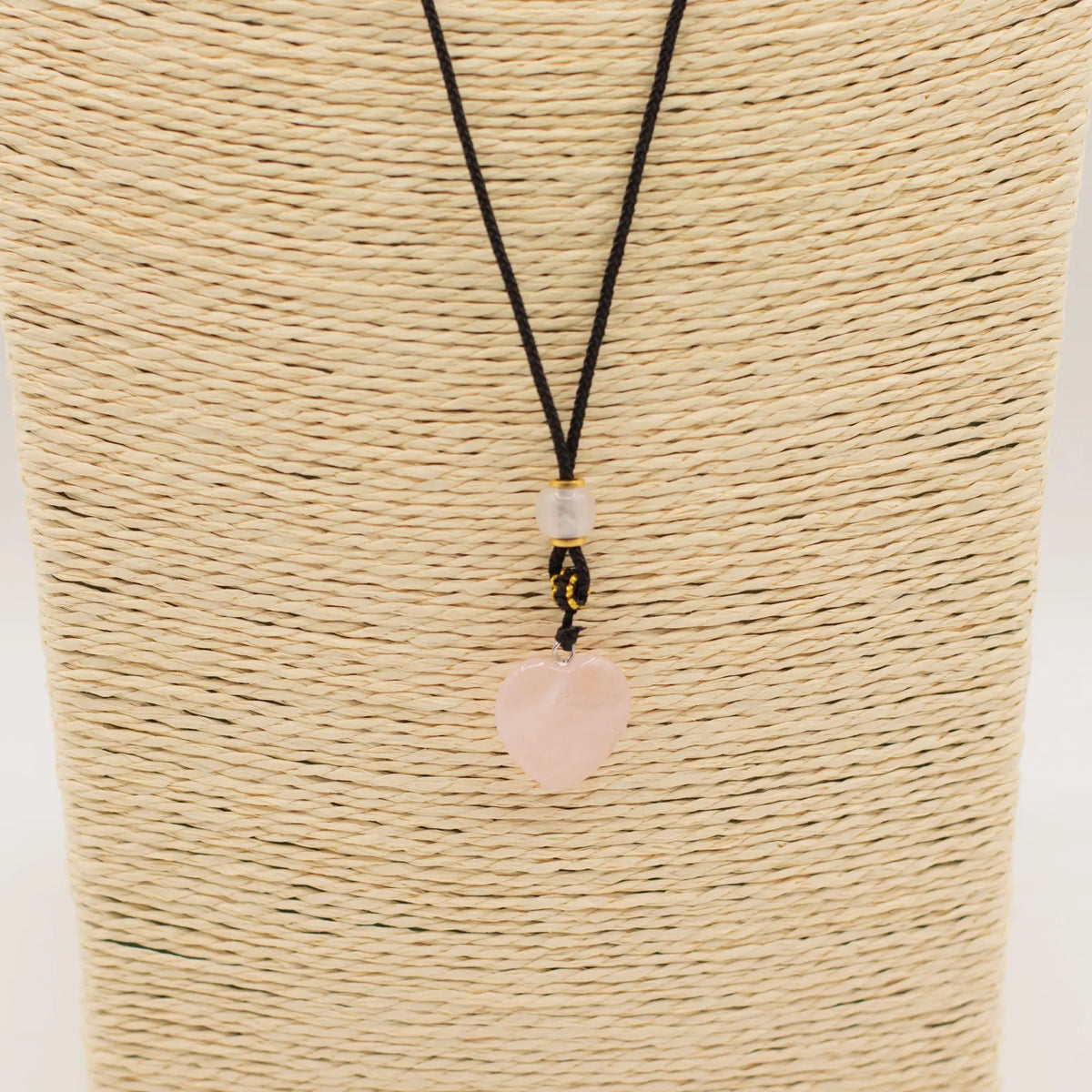 Collar de cordón negro con colgante en forma de corazón de cuarzo rosa y detalles en cuentas amarillas y transparentes.