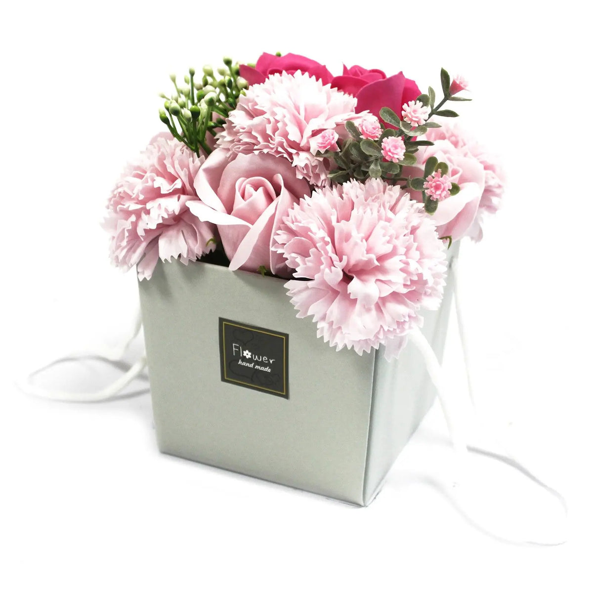 Bouquet de rosas y claveles de jabón en tonos rosa, presentados en una caja cuadrada gris con asas, fondo blanco.