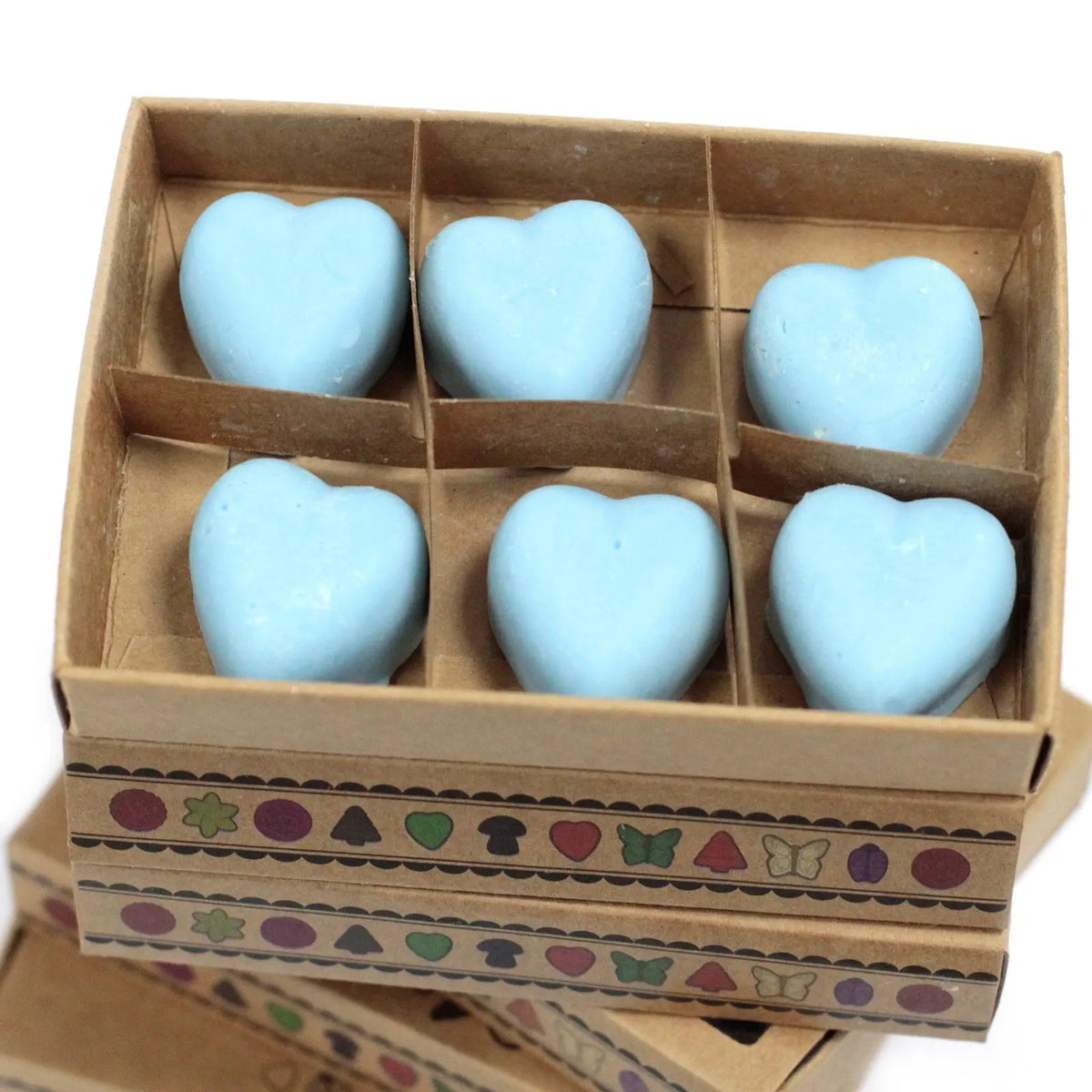 Caja de cartón con 6 ceras de soja azules en forma de corazón, sobre fondo blanco. Estilo artesanal.