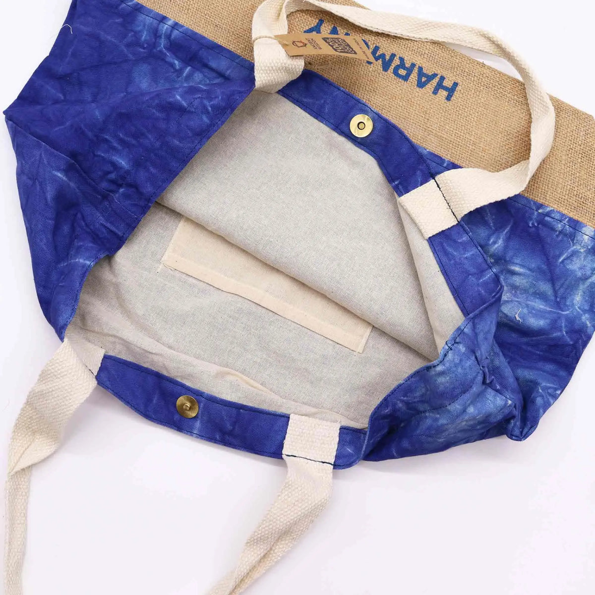 Bolsa tote de yute y algodón azul teñido, con asas claras, cierre de broche y bolsillo interior, vista superior.