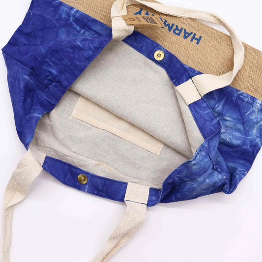 Bolsa tote de yute y algodón azul teñido, con asas claras, cierre de broche y bolsillo interior, vista superior.