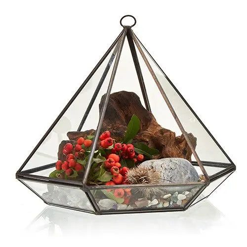 Terrario geométrico en forma de pirámide, vidrio transparente, base negra, decorado con ramas, piedras y bayas rojas.