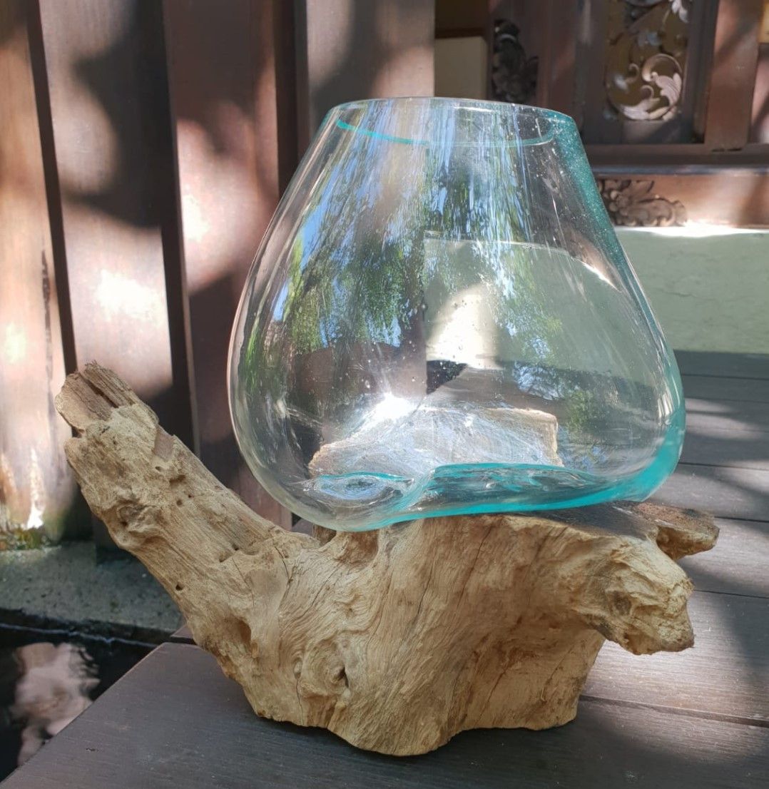 Tazón de vidrio transparente fundido sobre una base de madera natural con formas orgánicas.