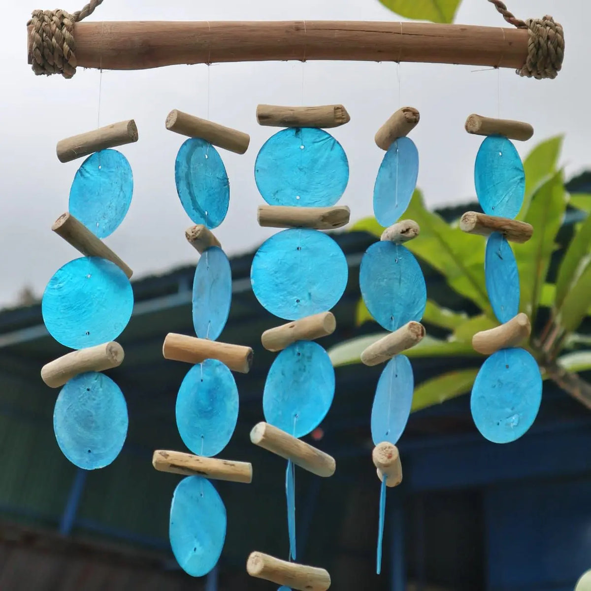 Carillón de madera flotante con discos azules de concha colgando de hilos en estilo natural y artesanal