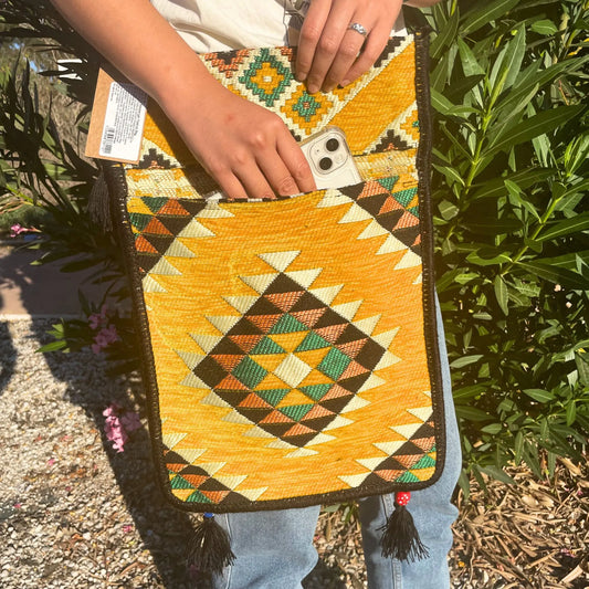 Bolso bandolera de kilim amarillo con patrón geométrico, detalles en verde y negro, acabado con borlas inferiores.
