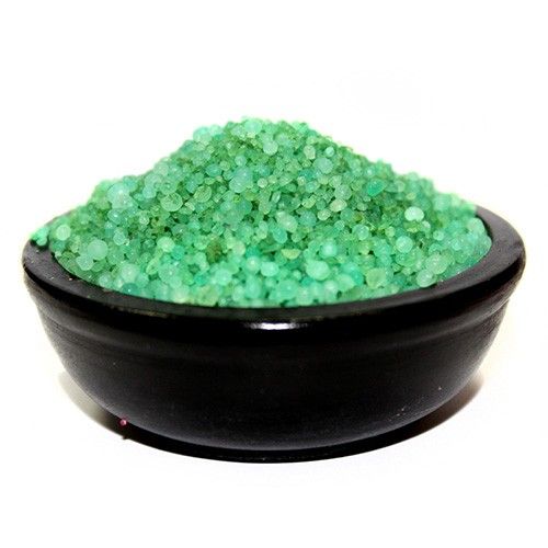 Cuenco negro pequeño lleno de gránulos aromáticos de color verde brillante sobre fondo blanco.