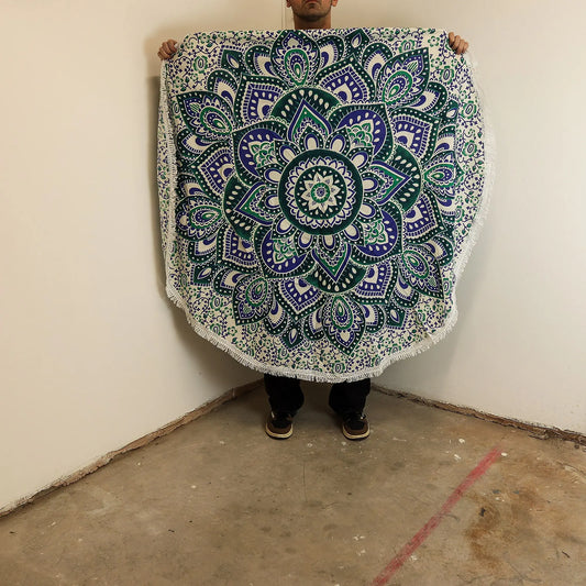 Tapiz redondo de algodón con estampado de mandala en tonos azul y turquesa, con flecos decorativos en el borde.