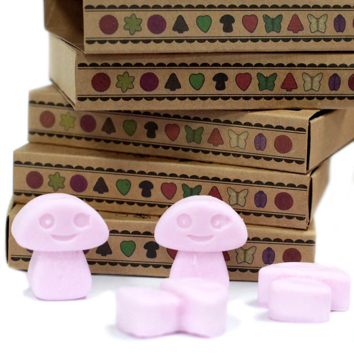 Cajas de cartón kraft apiladas con figuras de cera de soja rosa en forma de setas sonrientes frente a ellas.