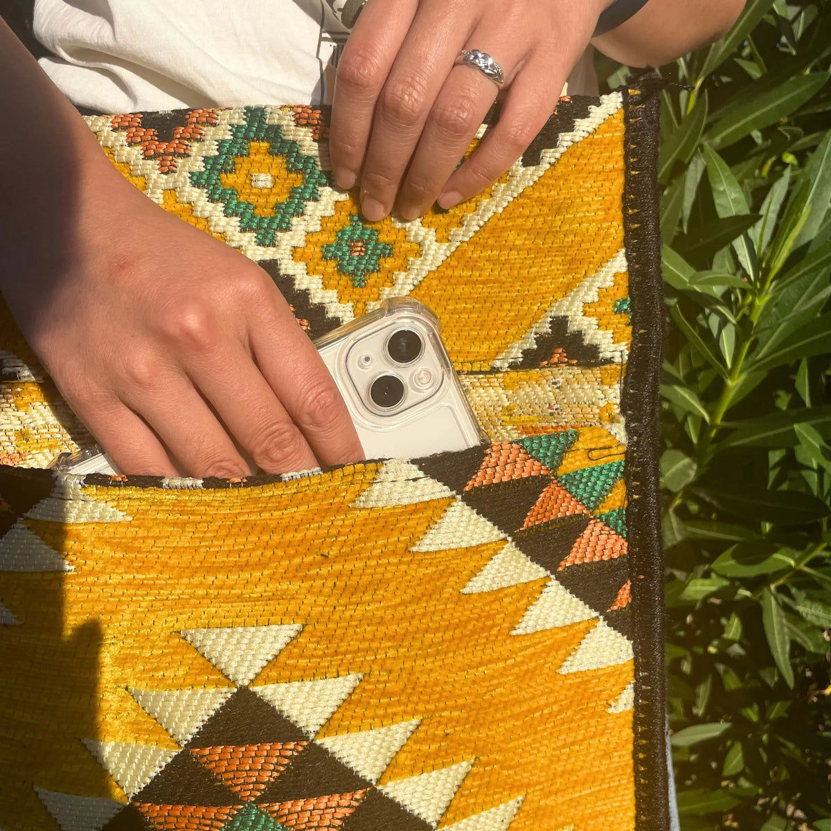 Bolsa tipo messenger de tela tejida estilo kilim con patrón geométrico amarillo, naranja, verde y negro.