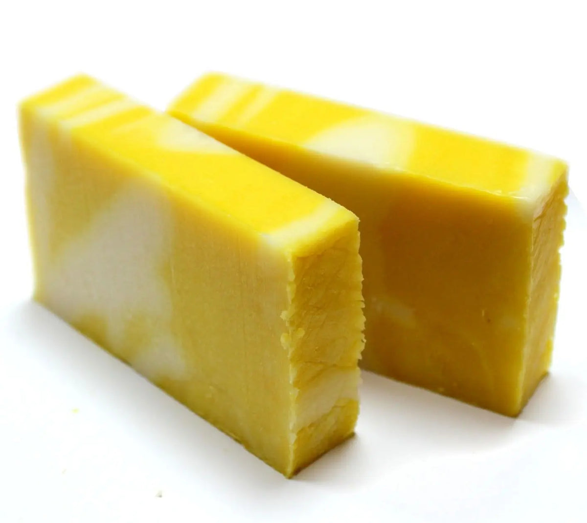 Dos barras rectangulares de jabón artesanal con remolinos en tonos amarillo brillante y blanco sobre fondo blanco.