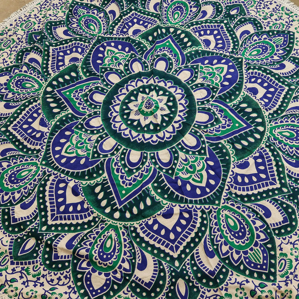 Tapiz de algodón redondo con diseño de mandala en tonos azul y turquesa sobre fondo blanco, con bordes de flecos.