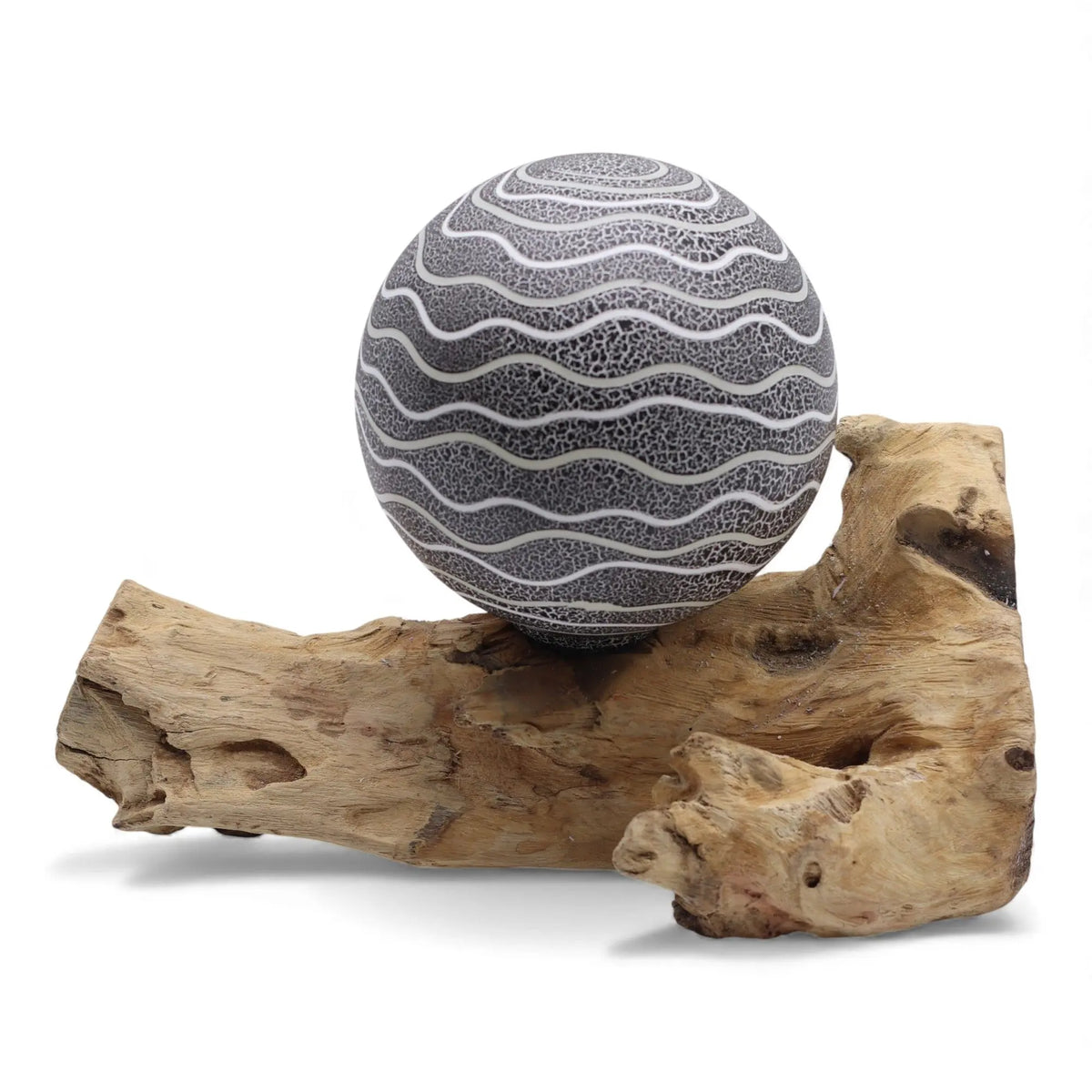 Lámpara de mesa esférica con rayas blancas sobre fondo gris texturizado, apoyada sobre una base de madera natural.