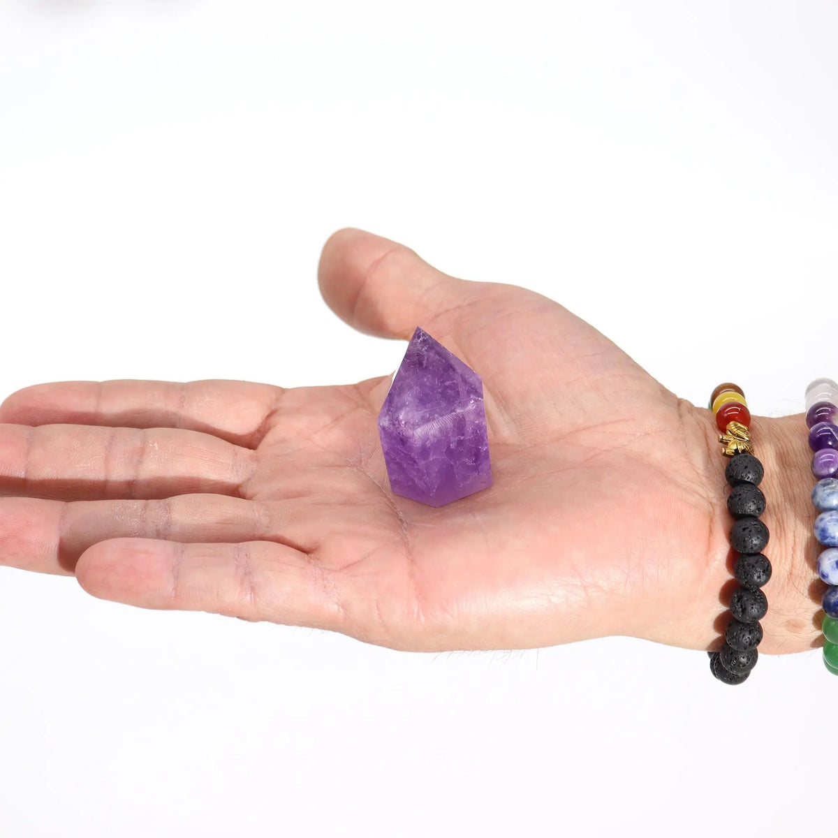 Cristal de amatista púrpura en forma de pico, sostenido en una mano masculina, fondo blanco.