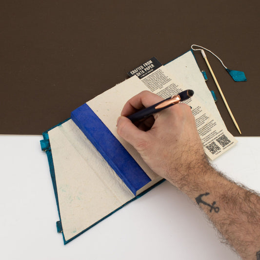 Cuaderno artesanal con cubierta azul, papel reciclado y detalles en verde, ideal para notas y escritura creativa.