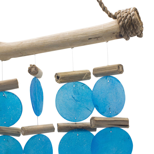Carillón artesanal con madera flotante y discos circulares de color azul suspendidos de hilos sobre fondo blanco