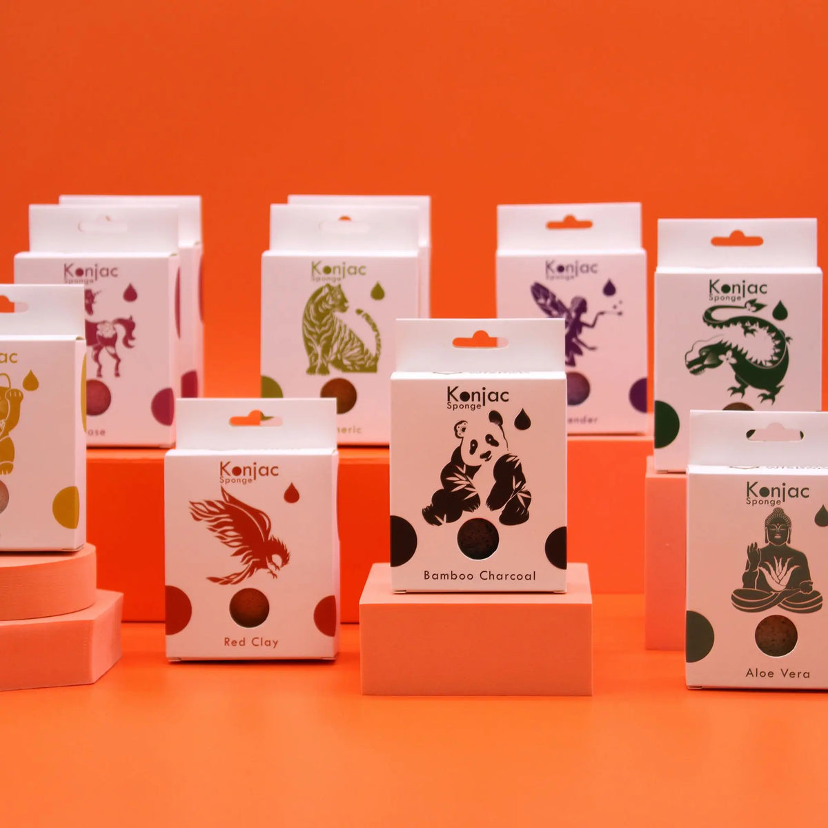 Varias cajas blancas de esponjas faciales sobre soportes naranjas con ilustraciones de animales y plantas en fondo naranja