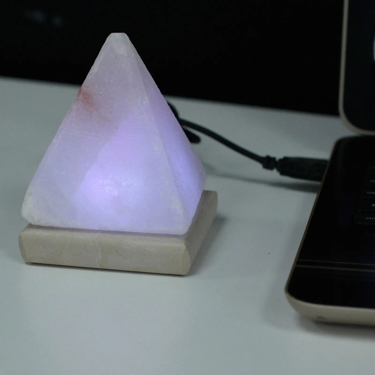 Lámpara de sal piramidal blanca sobre base cuadrada, conectada vía USB, emitiendo luz LED multicolor.