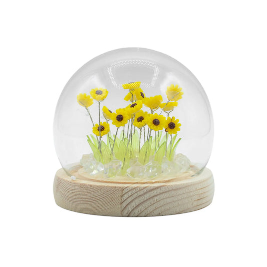 Domo de cristal con 20 girasoles amarillos, hojas verdes y luces LED sobre base de madera circular. Marca Ancient Wisdom.