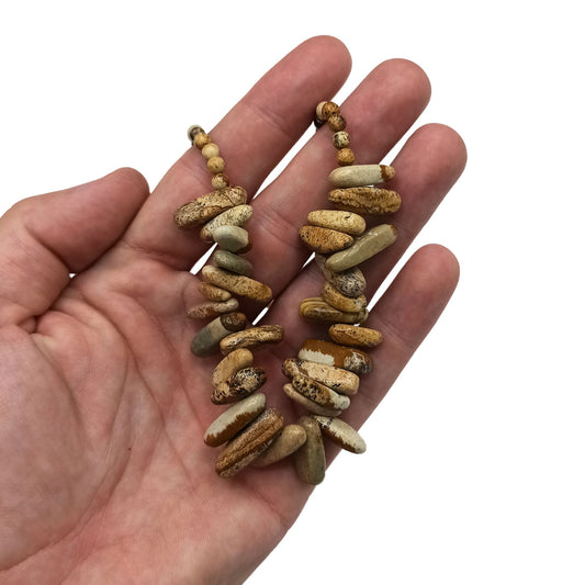 Collar de piedra del mapa en tonos beige y marrón con gemas alargadas sostenido sobre una mano abierta.