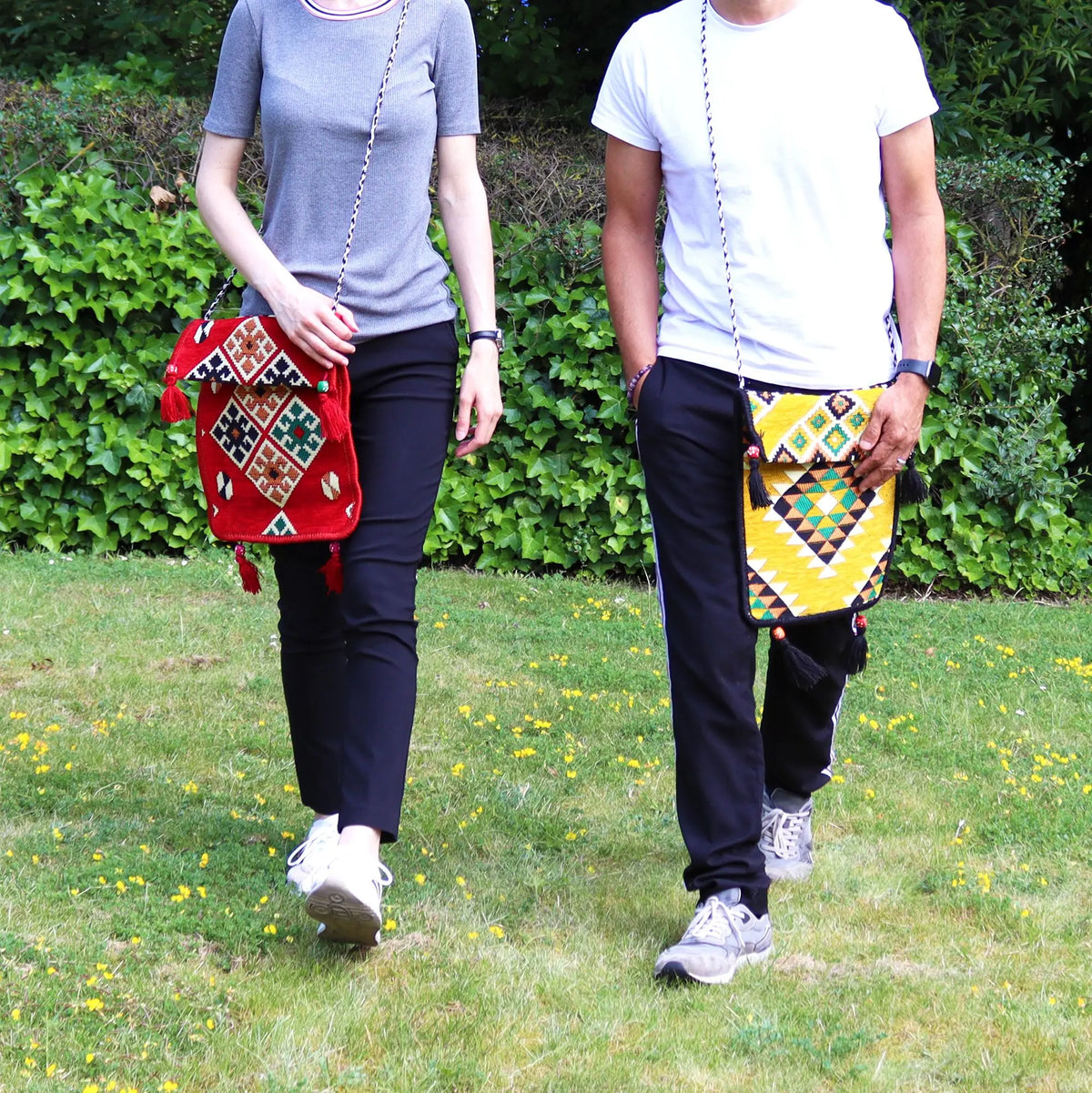 Bolsos tipo messenger de tela estilo Kilim, con patrones geométricos coloridos y borlas, colgados al hombro en el campo.