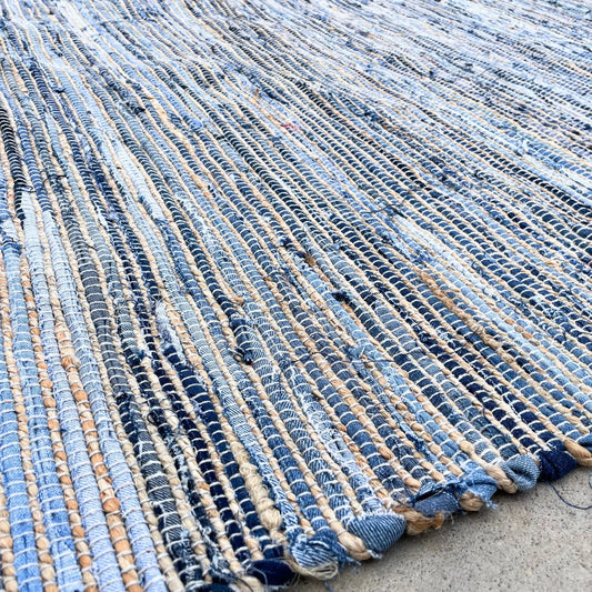 Alfombra artesanal de yute y algodón reciclado en tonos azules, con textura trenzada y diseño rústico.