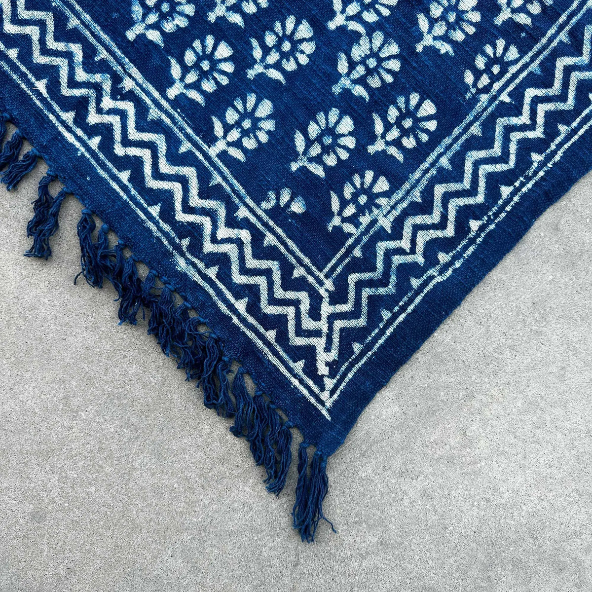 Alfombra azul marino de algodón con diseño floral y flecos, estilo bohemio. Ideal para decoración interior.