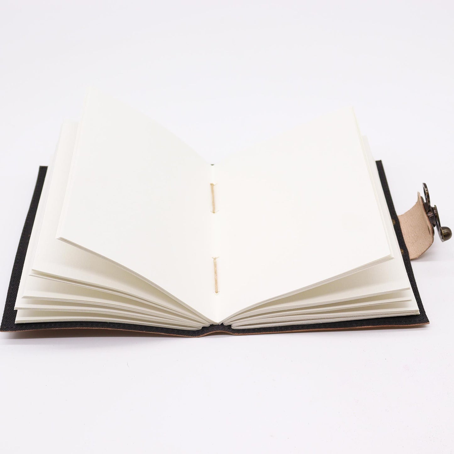 Cuaderno en cuero marrón, tapas negras, hojas en blanco, estilo artesanal y elegante, ideal para escribir o dibujar.