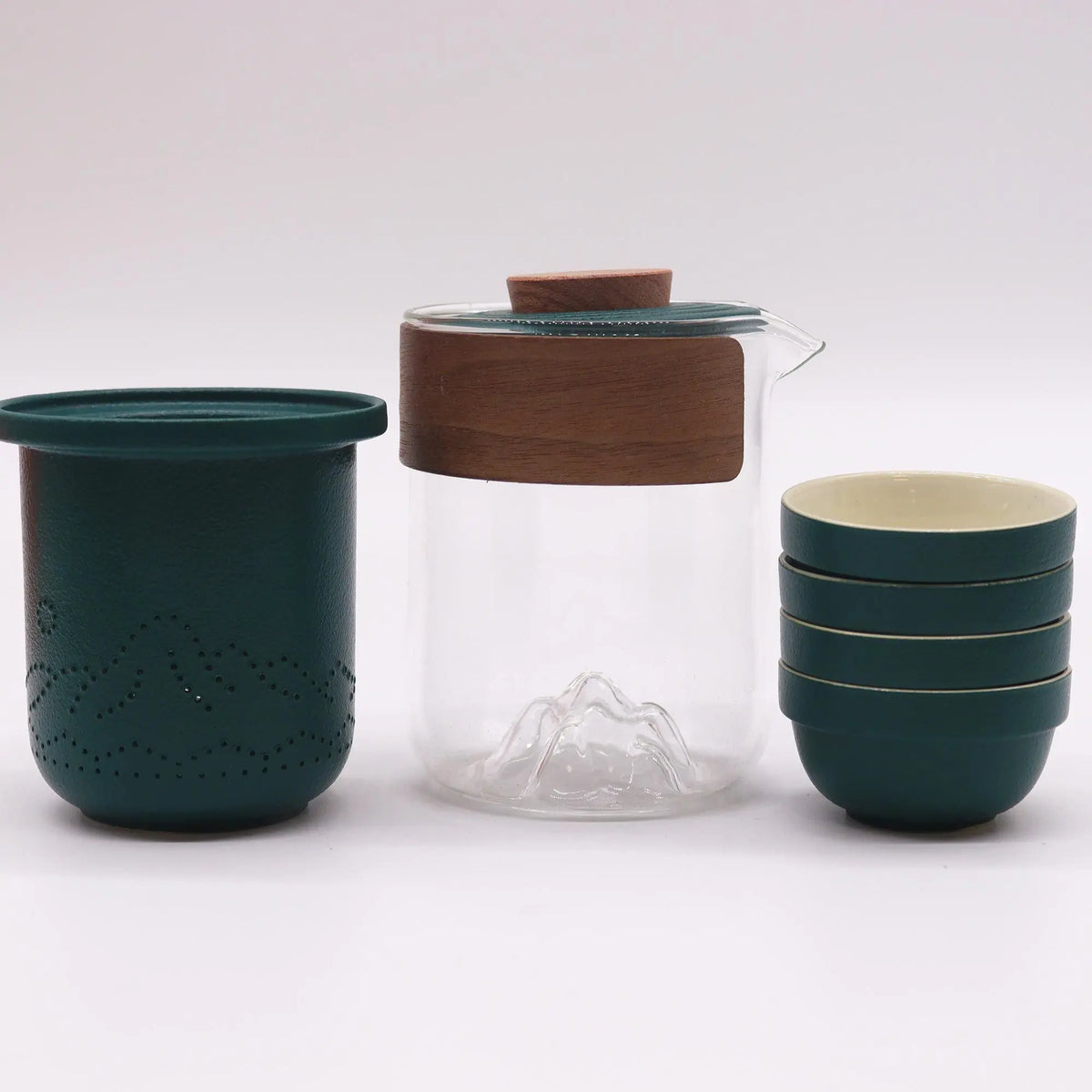 Set de té portátil: tetera de cristal con tapa de madera, filtro verde con relieve y cuatro tazas a juego.