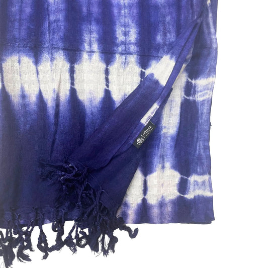 Estola de lino y rayón azul índigo con diseño de rayas estilo tie-dye y flecos en los extremos. Textura tejida.