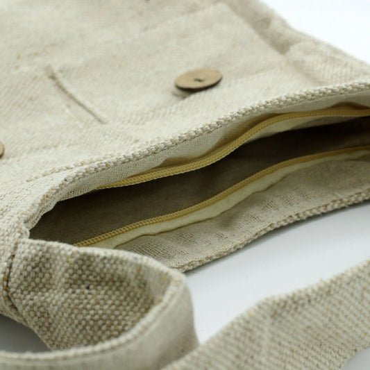 Bolso mediano de tela color natural, con dos bolsillos frontales, cierre de cremallera y botones decorativos de madera.
