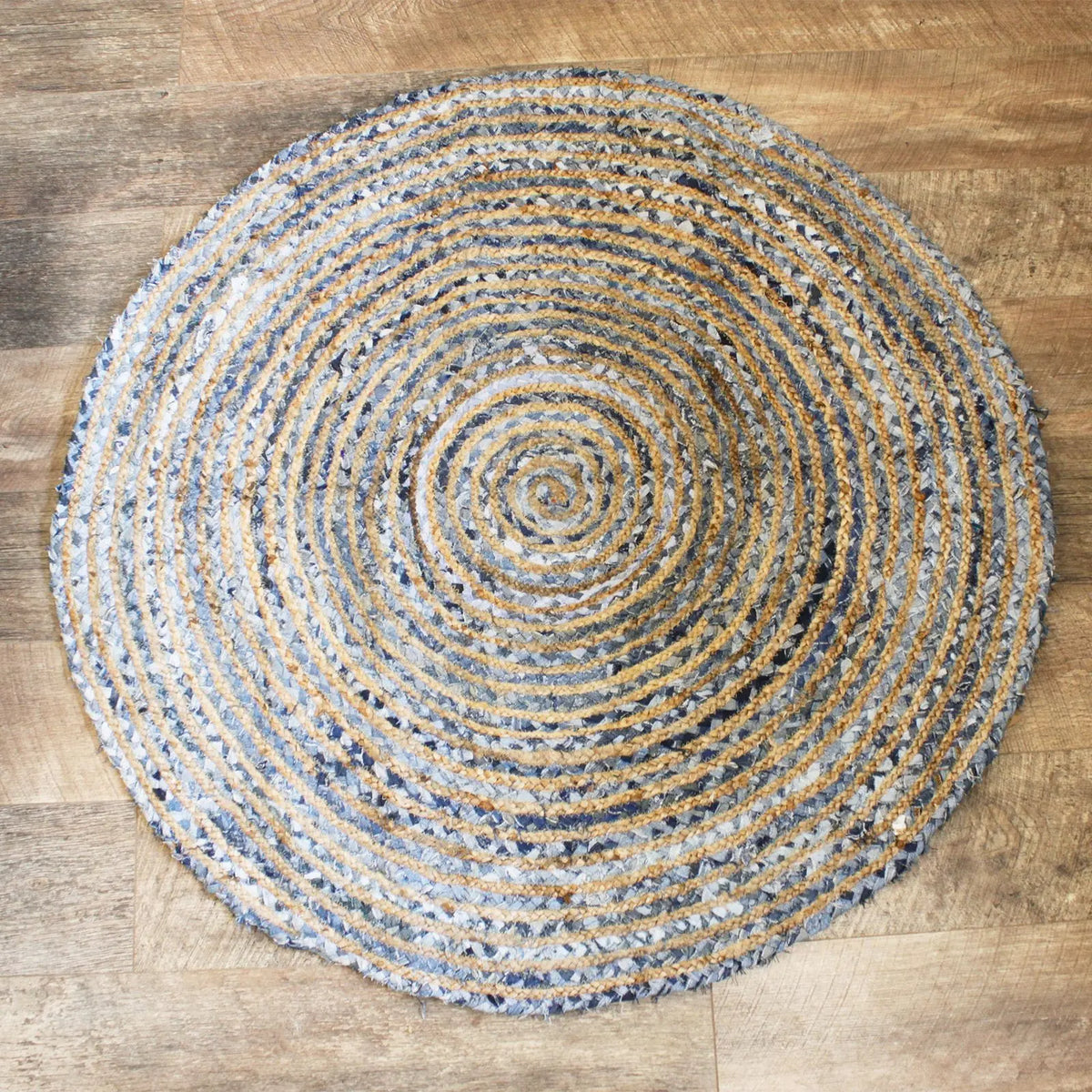 Alfombra redonda de 120 cm tejida en espiral con fibras de yute natural y tiras de mezclilla azul.