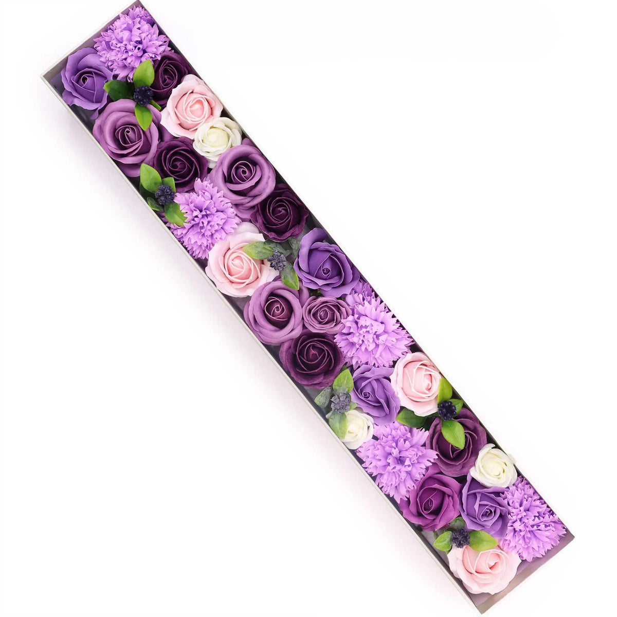 Caja rectangular alargada con rosas y claveles de jabón en tonos morados, rosas y blancos decorada con hojas verdes