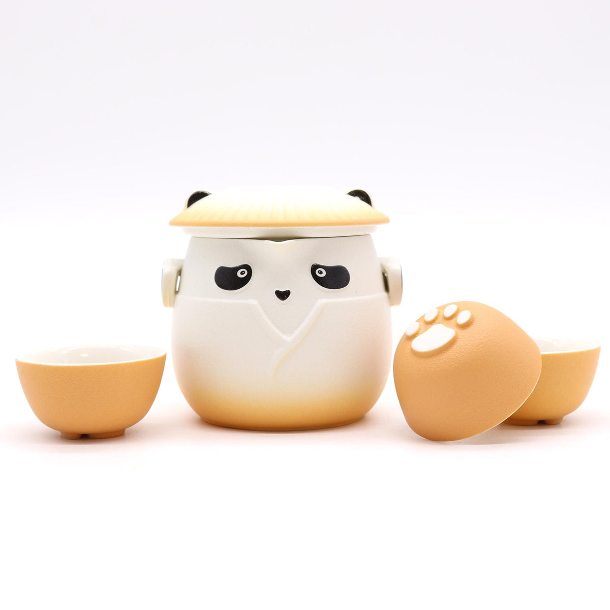 Juego de té cerámico: tetera con diseño de panda y tres tazas naranja con relieve de huella sobre fondo blanco.