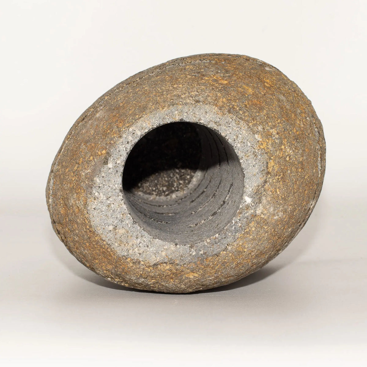 Jarrón de piedra gris y marrón, forma ovalada, acabado rústico, ideal para decoración moderna.