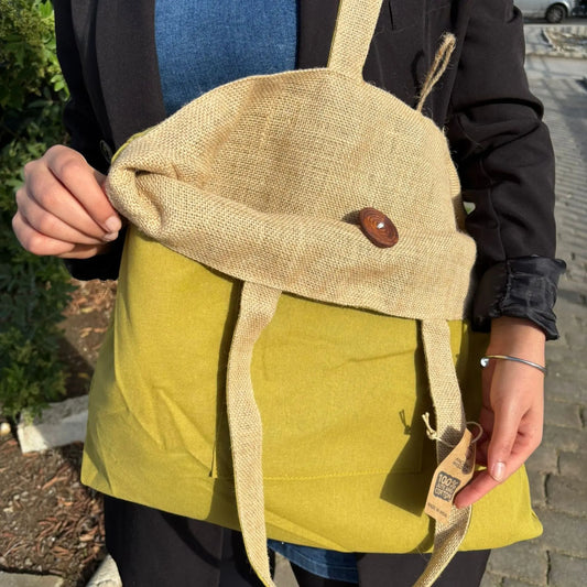 Bolsa reversible de yute natural y algodón color pistacho, con botón de madera y asas largas, colgada al hombro.