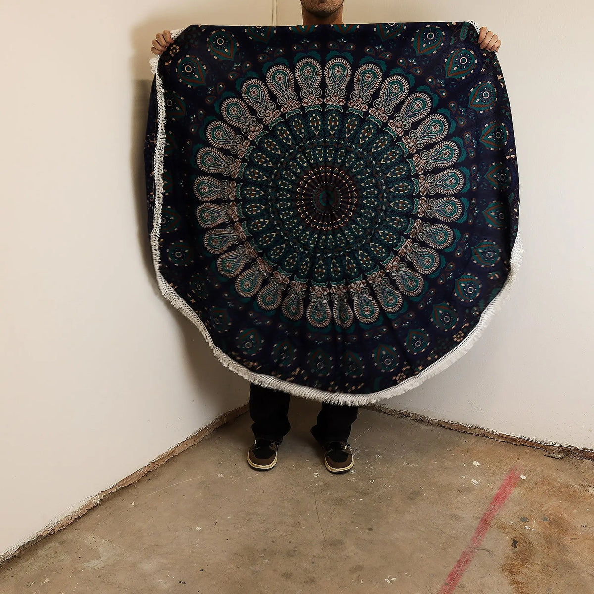 Tapiz redondo de algodón azul pavo real con estampado de mandala detallado y bordes con flecos blancos.