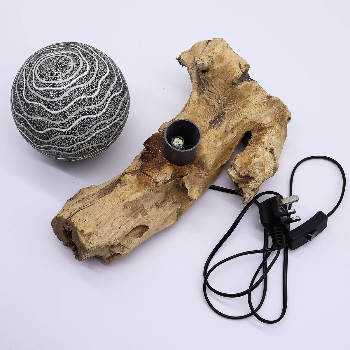 Lámpara de madera rústica con base de tronco natural y pantalla esférica gris con diseño de rayas y textura agrietada