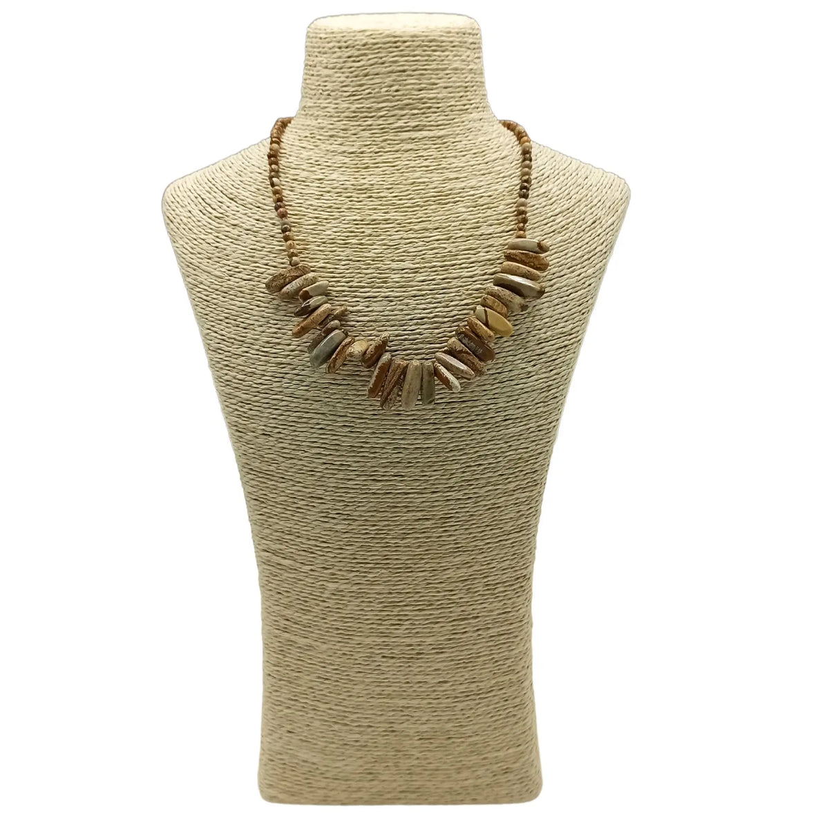 Collar de piedras naturales alargadas en tonos beige y marrón sobre un busto de exhibición de fibra natural.