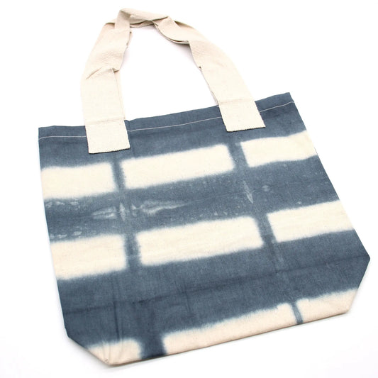 Bolsa de algodón natural con estampado tie-dye de rectángulos grises y asas color crema sobre fondo blanco.