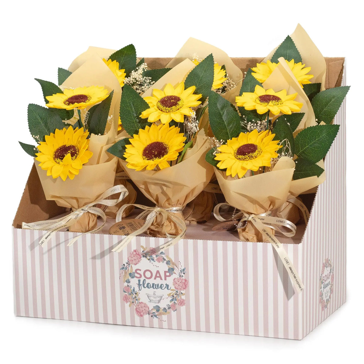 Expositor con ramos de dos girasoles de jabón, envueltos en papel kraft beige y decorados con hojas verdes y lazos.