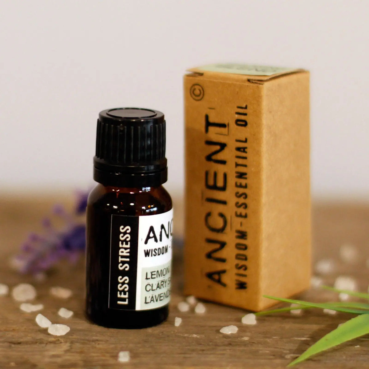 Frasco de vidrio ámbar y caja de cartón marrón de Aceites Esenciales Ancient Wisdom Anti Estrés sobre madera.