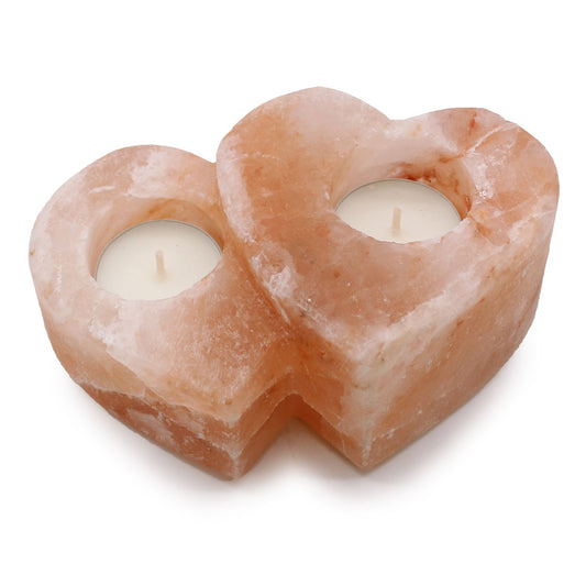 Portavelas de sal del Himalaya con forma de dos corazones unidos, en tono rosado, con dos velas blancas en el interior.