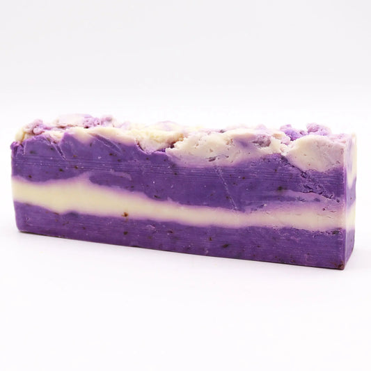 Barra de jabón artesanal Ancient Wisdom de lavanda, con capas texturizadas en tonos violeta y crema. Fondo blanco.