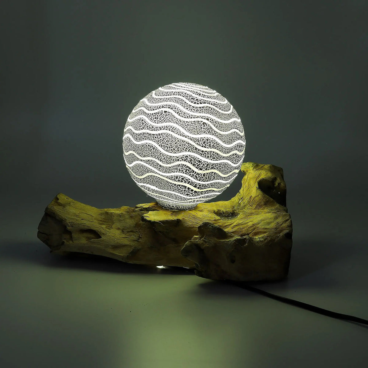 Lámpara esférica iluminada con patrón de ondas sobre una base de madera natural, estilo rústico y moderno.