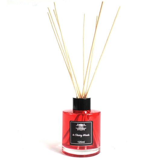Difusor aromático de 120ml con líquido rojo, frasco de vidrio cilíndrico, tapón negro y varillas de madera clara.
